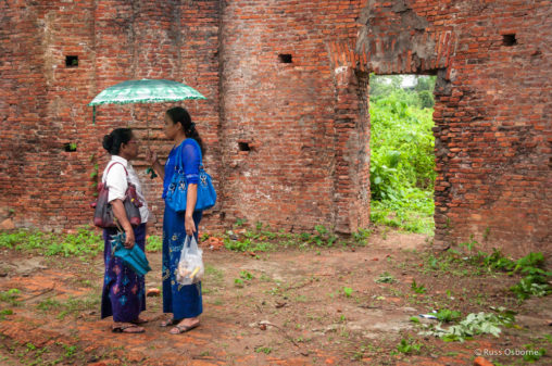 Two Burmese women standing under an umbrella