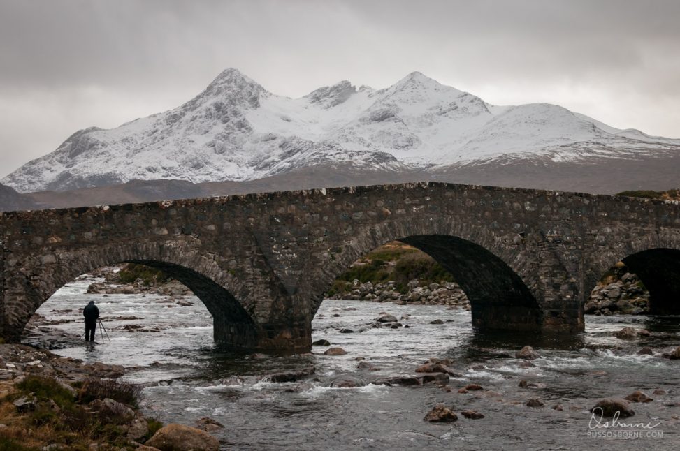 Stone bridge over a river with mountains in the background